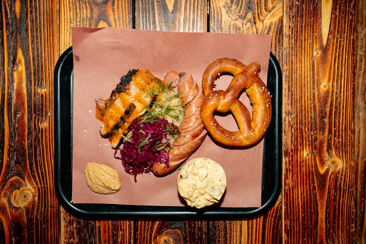 Matbricka med  pretzel, potatissallad, bratwurst, fläsksida & ingefärsglaze, senap, surkål och rödkål